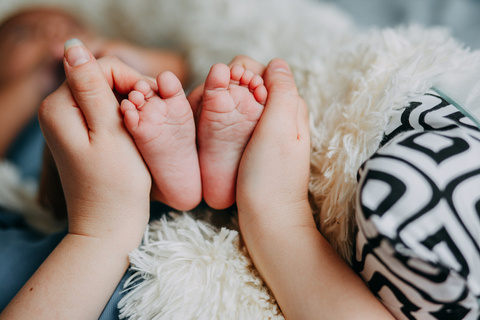 Handen rond de voetjes van een baby